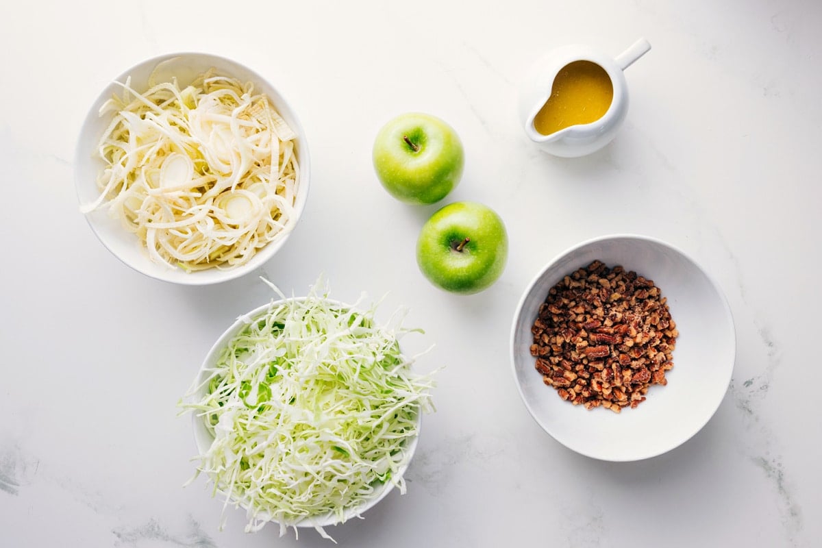 All the ingredients in this recipe prepped out for easy assembly including the apples, cabbage, pecans, and dressing.