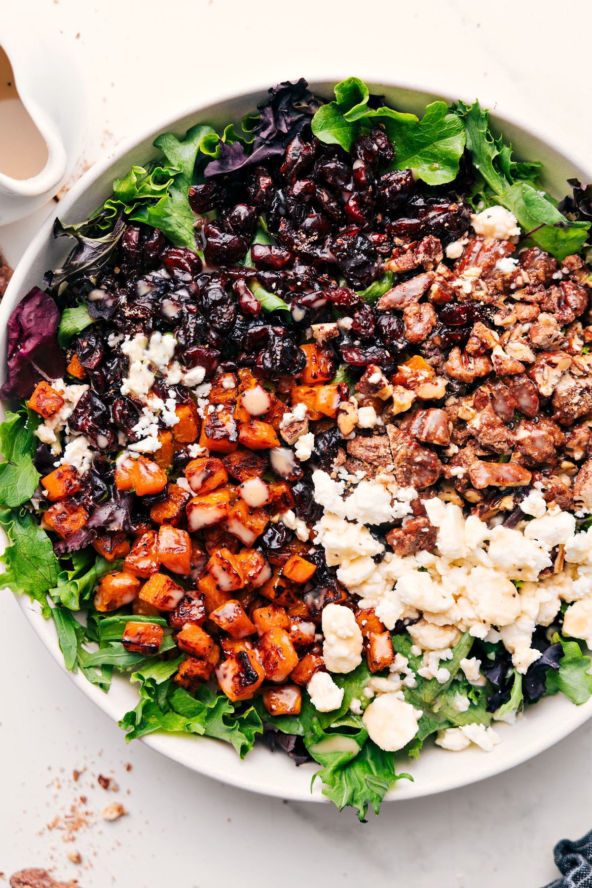 Delicious and easy-to-make Butternut Squash Salad Butternut squash salad in a large bowl with dressing drizzled over the top.