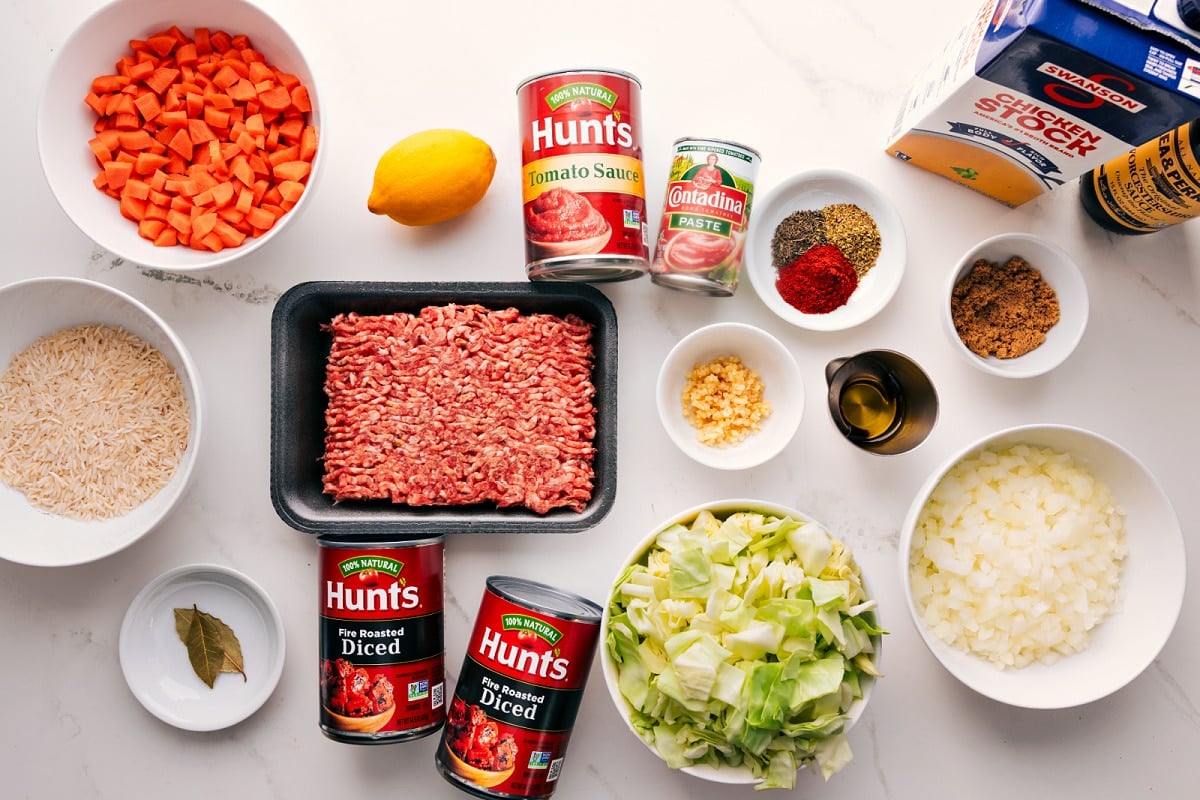 All the ingredients in this recipe prepped out for easy assembly including rice, veggies, tomatoes, sausage, seasonings, cabbage, stock, and worchestershire sauce.