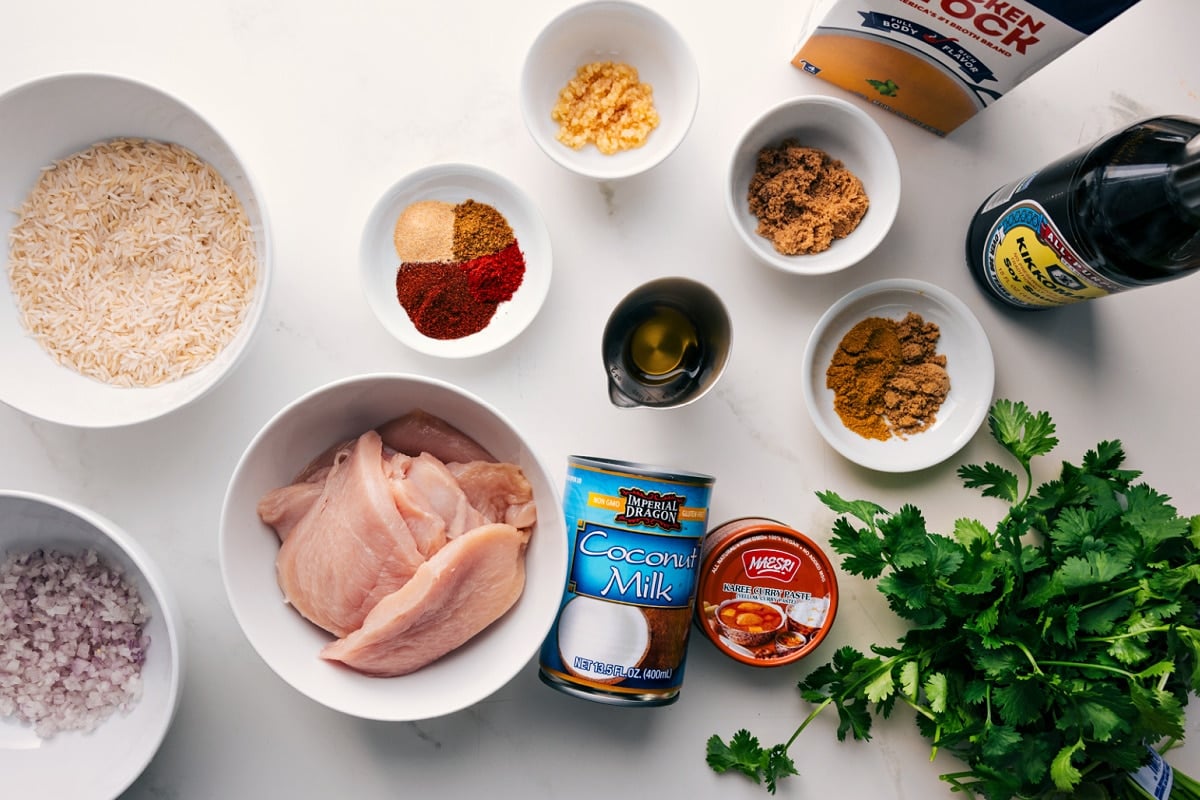 All the ingredients in this recipe prepped out for easy assembly including the rice, shallots, chicken, spices, seasonings, coconut milk, curry paste, soy sauce, and chicken stock.